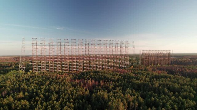 Aerial view of the massive Duga 1 Receiver radar array rising above the dense pine forest in the exclusion zone of Chernobyl, Kyiv Oblast, Ukraine.