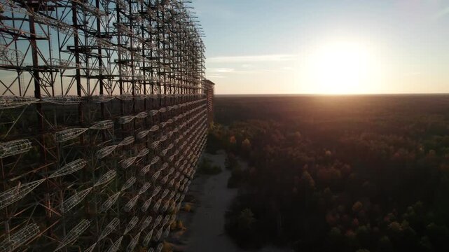 Aerial view of the massive Duga 1 Receiver radar array rising above the surrounding forest at sunset in Chernobyl, Kyiv Oblast, Ukraine.