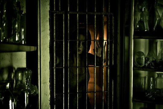 Haunted laboratory with a trapped figure behind bars and eerie glass containers