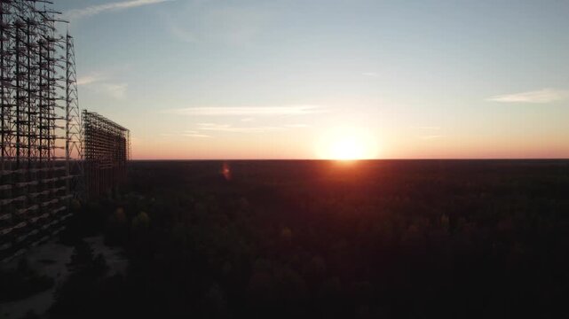 Aerial view of Duga 1 Receiver radar array at sunset with silhouettes of the massive steel structure against the glowing horizon in Chernobyl, Kyiv Oblast, Ukraine.