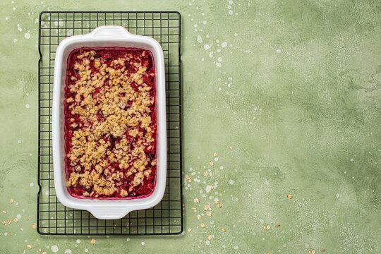 Homemade Autumn plum crumble in baking dish. Fruit crisp with oat topping. Oatmeal pie. Top view, copy space.
