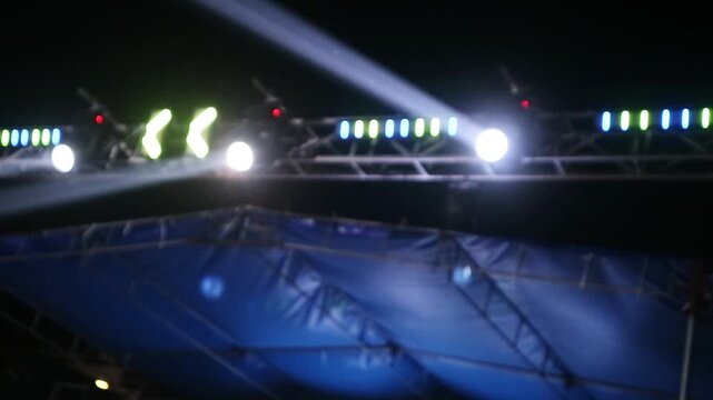 Bright stage lights shining over a dark outdoor concert venue at night.