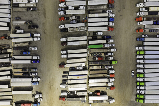 Aerial view of a large logistics lot filled with rows of semi-trucks and trailers parked in an organized grid in Chicago, Illinois, United States.