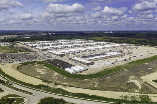 Aerial view of a large data center under construction with multiple long buildings, heavy machinery, and surrounding earthworks in Hoffman Estates, Illinois, United States.