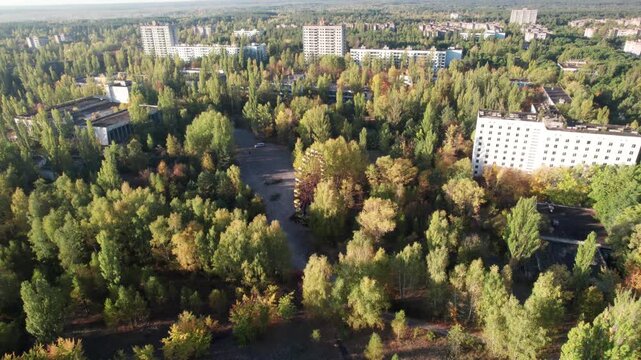 Aerial view of the abandoned Ferris wheel in the amusement park surrounded by overgrown trees and decaying apartment blocks in Prypyat, Kyiv Oblast, Ukraine.