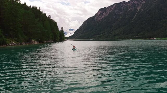 Woman paddleboarding on the scenic Achen Lake in Austria - drone shot