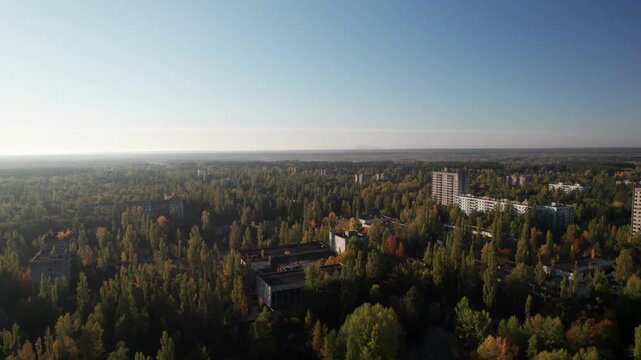 Aerial view of the abandoned city of Pripyat, showing decaying apartment buildings surrounded by overgrown forests and autumn foliage in Prypyat, Kyiv Oblast, Ukraine.