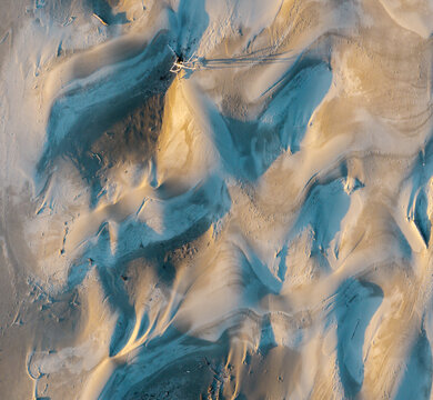 Aerial view of sand dunes along the Pacific Ocean coast with soft shadows and golden light in Bandon, Oregon, United States.
