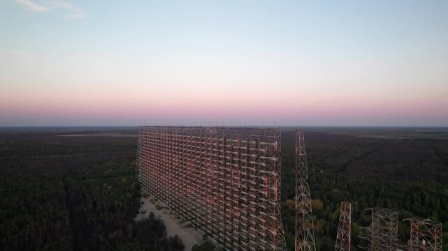 Aerial view of the massive Duga 1 Receiver radar array rising above the surrounding forest at sunset in Chernobyl, Kyiv Oblast, Ukraine.