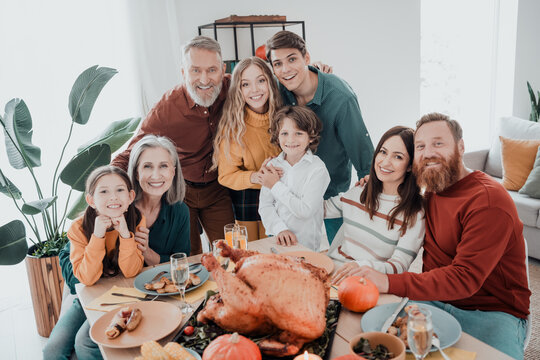Multi-generation family gathered for Thanksgiving dinner at home smiling around a festive table with roasted turkey and autumn decorations