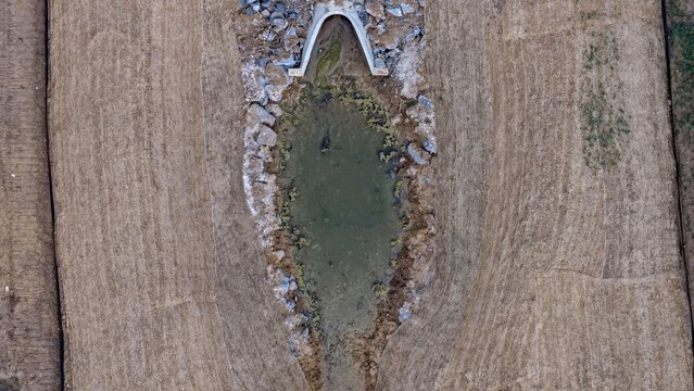 Aerial view of a concrete drainage culvert surrounded by rocks and dry fields in Longmont, Colorado, United States.