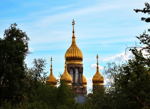 Wiesbaden, Hesse, Germany &ndash; Golden onion domes of Russian Orthodox Church of Saint Elizabeth framed by lush green trees.