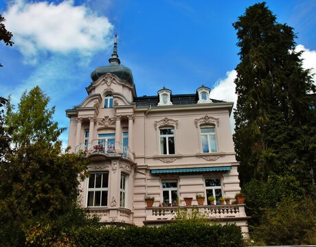 Wiesbaden, Hesse, Germany &ndash; Elegant historic villa with ornate facade, decorative balcony and distinctive tower surrounded by greenery.