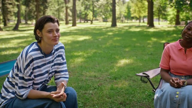 Diverse multiethnic group sitting in circle attending outdoor psychotherapy session with Caucasian therapist in park. Footage fits mental healthcare ads and psychological support campaigns
