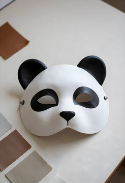 Childhood imagination and play, panda mask for costume party or creative performance with fabric swatches on a table for design and craft projects