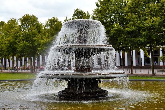 Wiesbaden, Hesse, Germany &ndash; Cascading fountain in front of Kurhaus Wiesbaden surrounded by green trees and landscaped grounds.