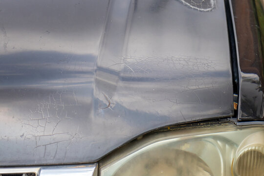 Close-up of damaged car after a traffic accident showing dented door and scratched bumper.Detailed shot of dented side door panel, broken headlight, and scratched front bumper on a pickup
