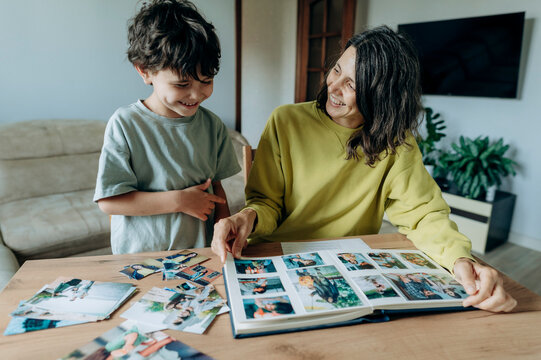 A mother and son look at a photo album together at home