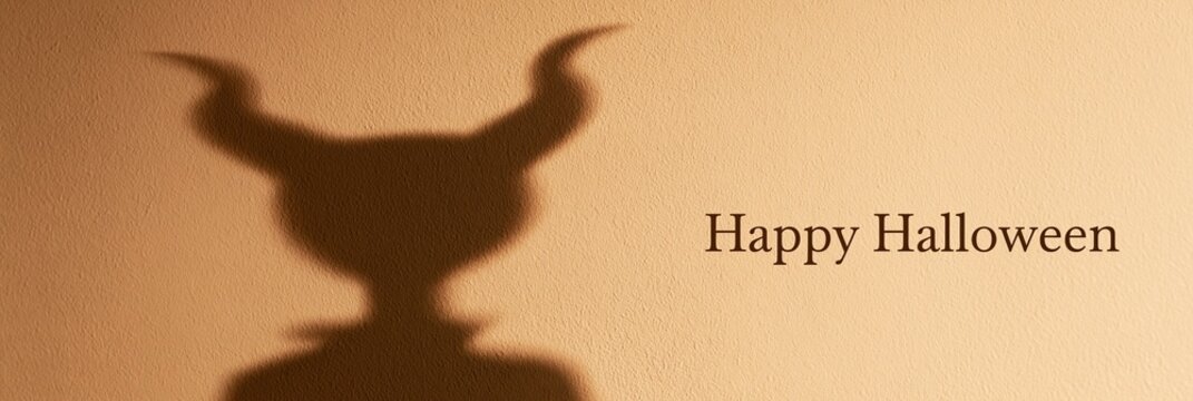 Scary shadow of devil horns on wall with text Happy Halloween, panoramic banner
