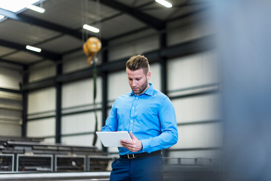 A male manager inspects a digital tablet in a production facility