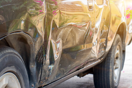Close-up of damaged car after a traffic accident showing dented door and scratched bumper.Detailed shot of dented side door panel, broken headlight, and scratched front bumper on a pickup