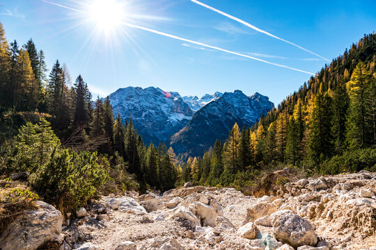 Autumn mountain landscape in South Tyrol with rocky trail and sun