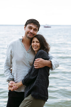 A happy couple hugs each other on the beach by the sea