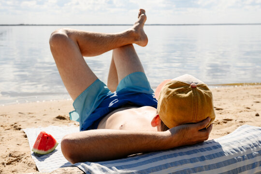 A male enjoys summer rest on a beach towel by the sea