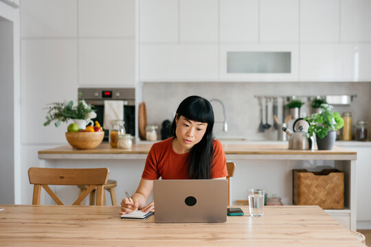 Entrepreneur working with laptop and notebook at kitchen table