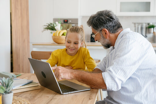 Grandfather and child learning together at home using a laptop