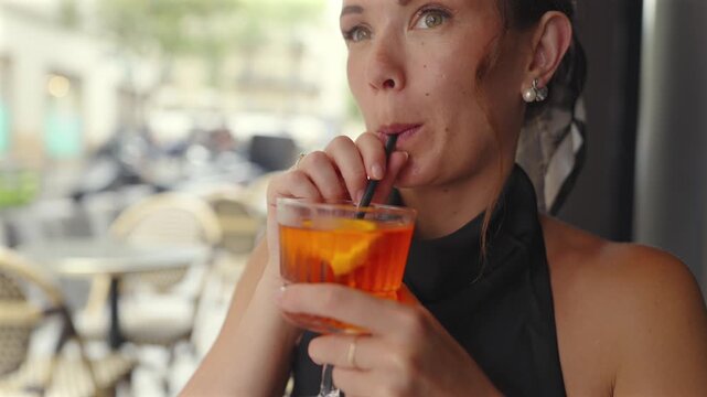 Close up of woman sipping orange cocktail at Paris cafe