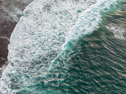 Aerial view of ocean waves crashing onto the sandy shore of Gunungkidul Regency, Special Region of Yogyakarta, Indonesia.