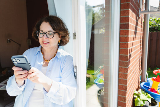 Mature woman reads a message on her smartphone at home
