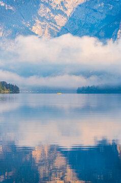 A yellow boat floats on the calm water of Lake Bohinj