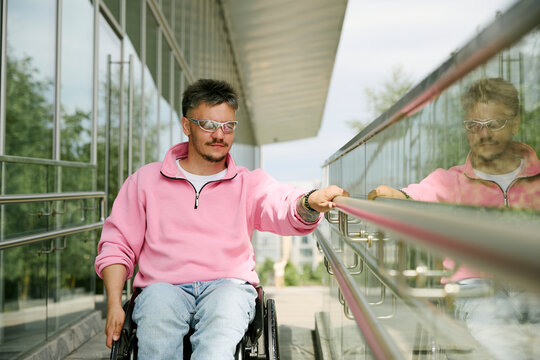 A man in a wheelchair uses a ramp outside a modern city building