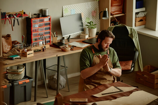 Male artisan works with leather at a table in his workshop