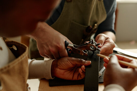 Man and woman craft a leather belt in a workshop