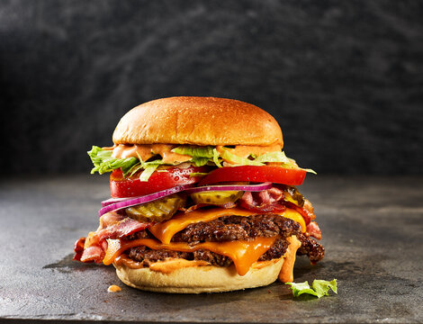 A delicious double smashburger sits on a dark stone table