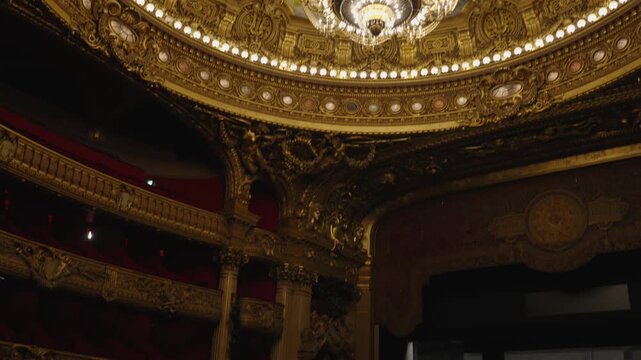 Ornate chandelier beneath painted ceiling at Palais Garnier