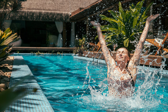 Brazil, Porto Seguro, woman splashing with water in the swimming pool