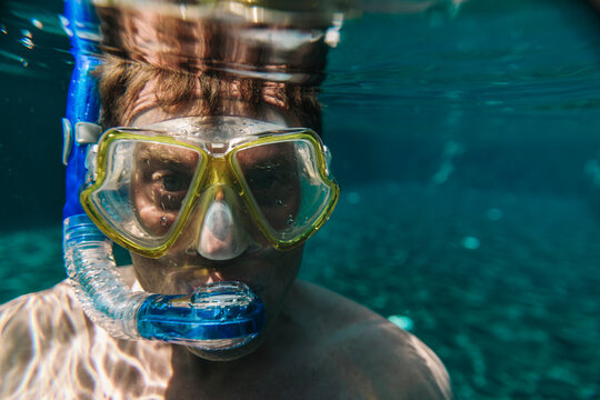 Portrait of man with diving goggles and snorkel underwater in a swimming pool