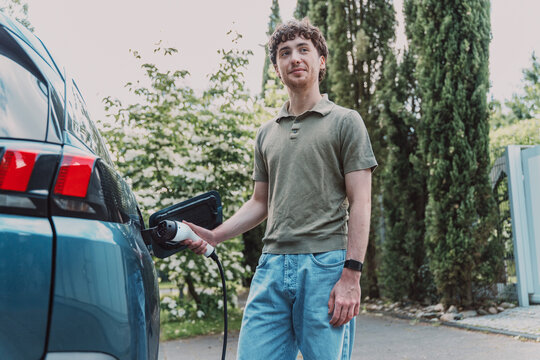 Young man charges his electric vehicle at home in Germany