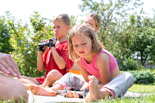 Mother, boy and girl lift a dumbbell outdoors in the garden