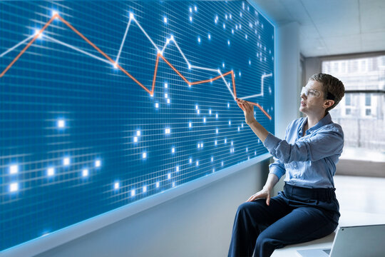 Businesswoman analyzes financial graph on digital screen in office