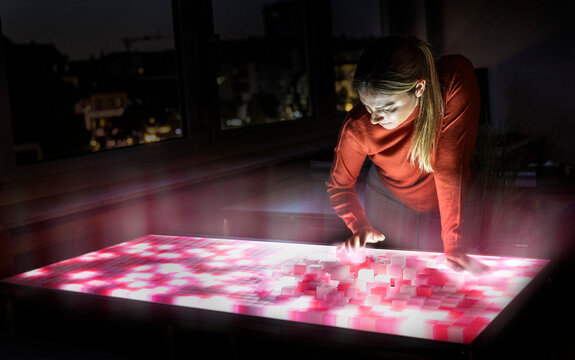 Woman analyzes AI data on a glowing screen in the office at night