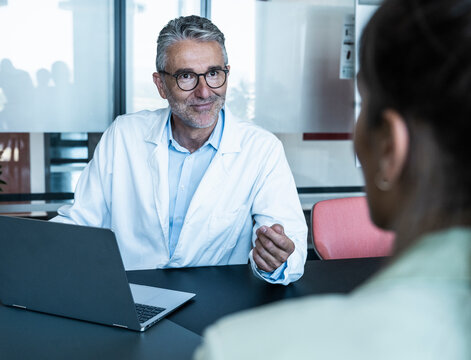 Male doctor gives advice to a female patient at the clinic desk