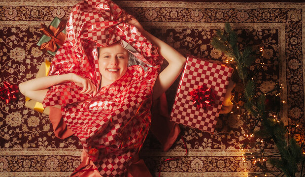 Tired woman unpacks Christmas gifts on the carpet at home