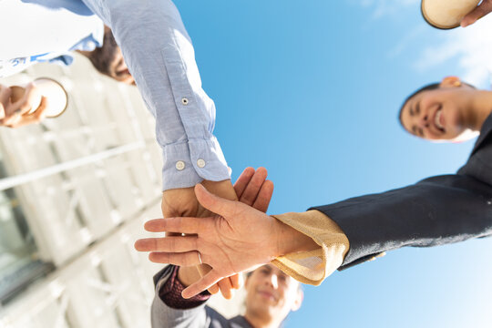 Business team putting hands together outdoors showing teamwork
