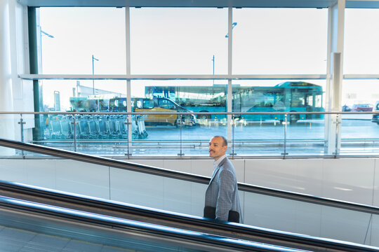 Businessman stands on escalator at airport terminal in Spain