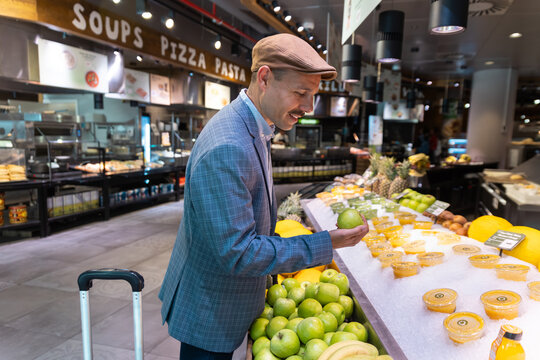 Smiling businessman chooses a fresh apple at an airport restaurant